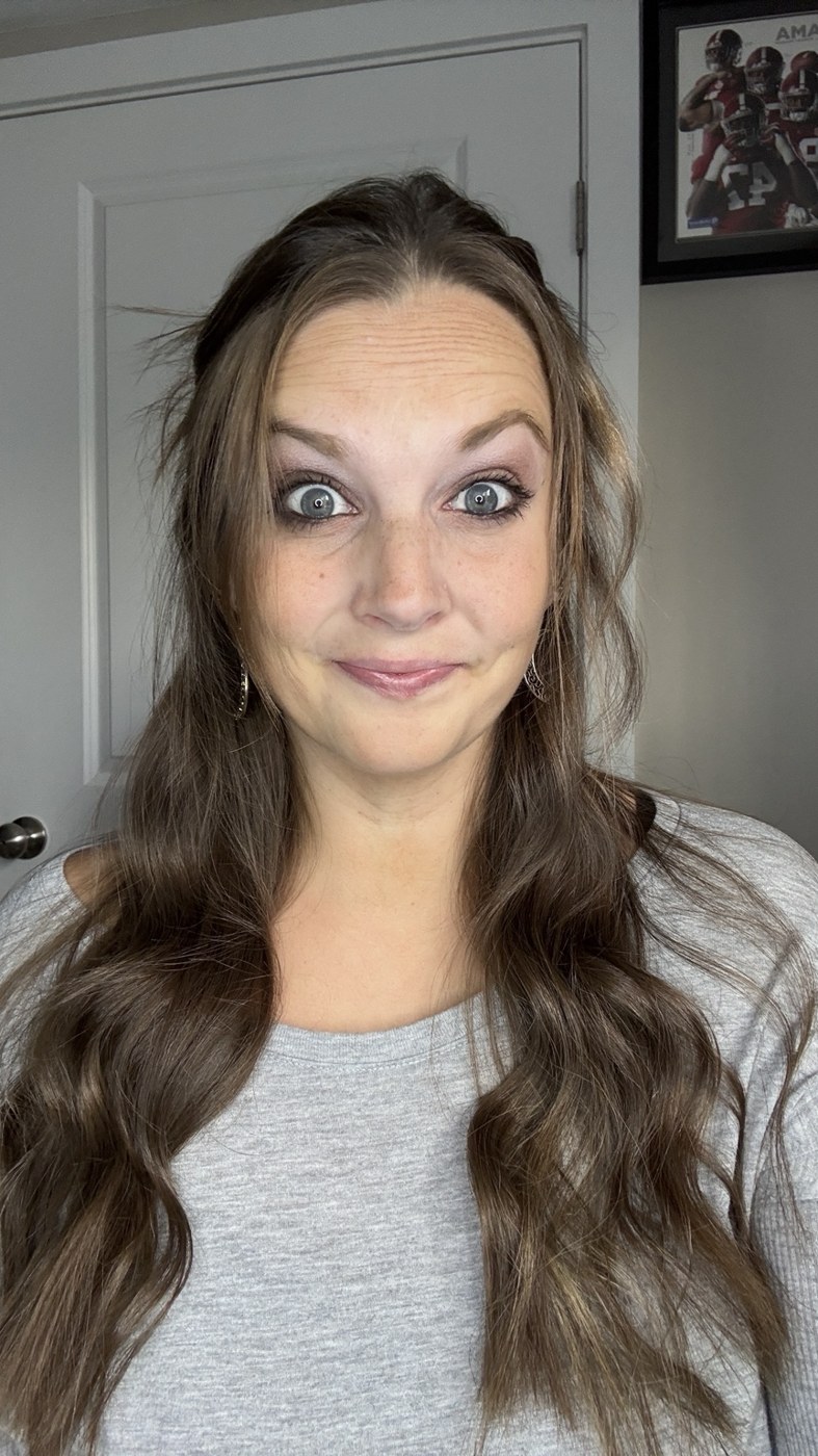 Kayla with long brown hair, wearing a gray top